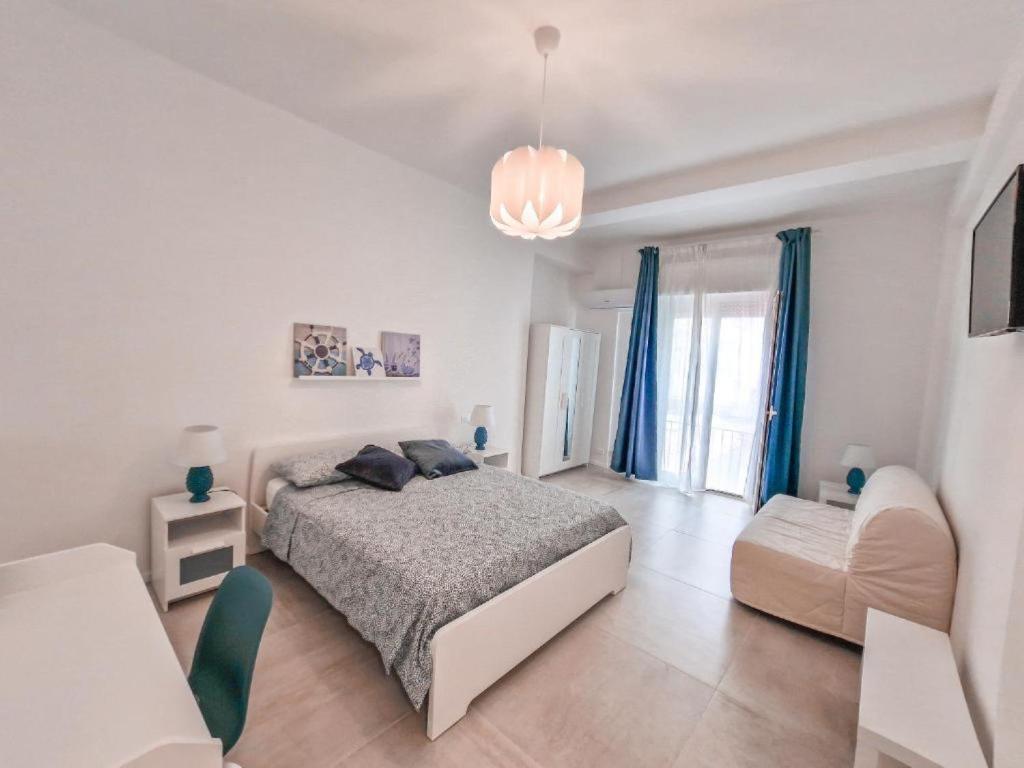 een witte slaapkamer met een bed en een stoel bij Holy Dove by Wonderful Italy in Cefalù