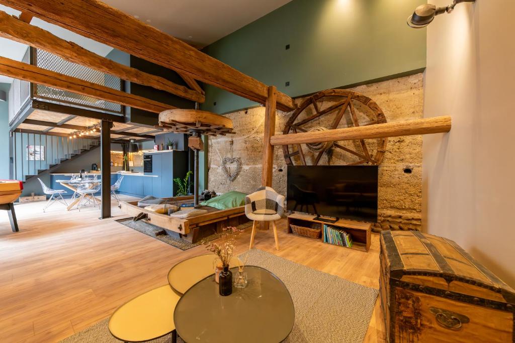 - un salon avec un mur en pierre et une grande télévision dans l'établissement La grange moderne aux portes de Lyon, à Vourles
