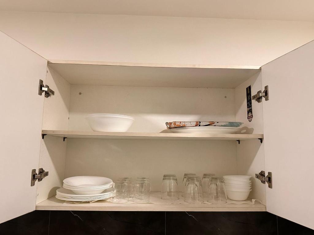 a cupboard filled with glasses and bowls and plates at Modern 2BR Central Apartment Lahore Zameen Opal in Lahore