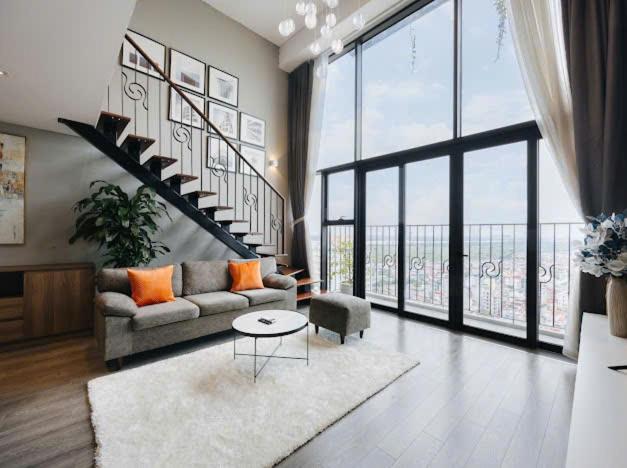 a living room with a couch and a large window at Hi-Home Suites - Penstudio Westlake Hanoi in Hanoi