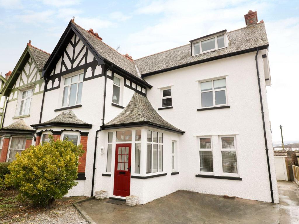 una casa blanca con una puerta roja en 51 Trinity Avenue, en Llandudno