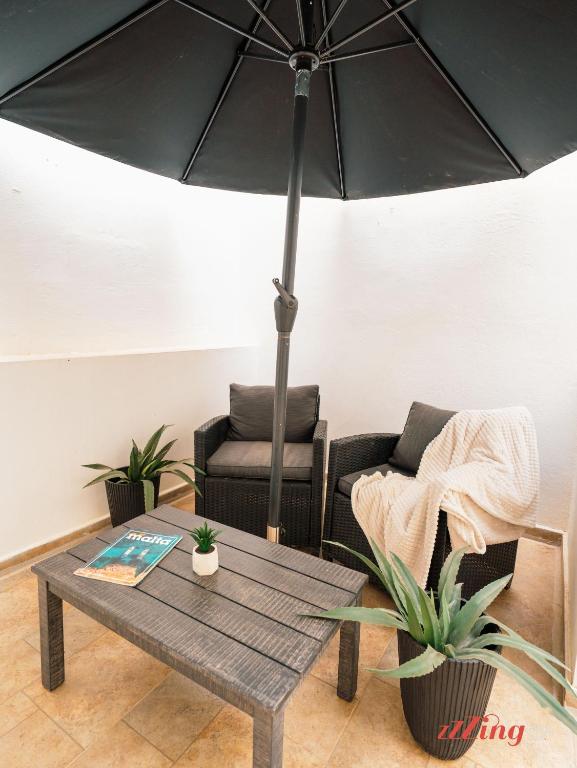 a living room with a table and a chair and an umbrella at Marsaskala Duplex with Private Patio Near Promenade in Tas-Sienja