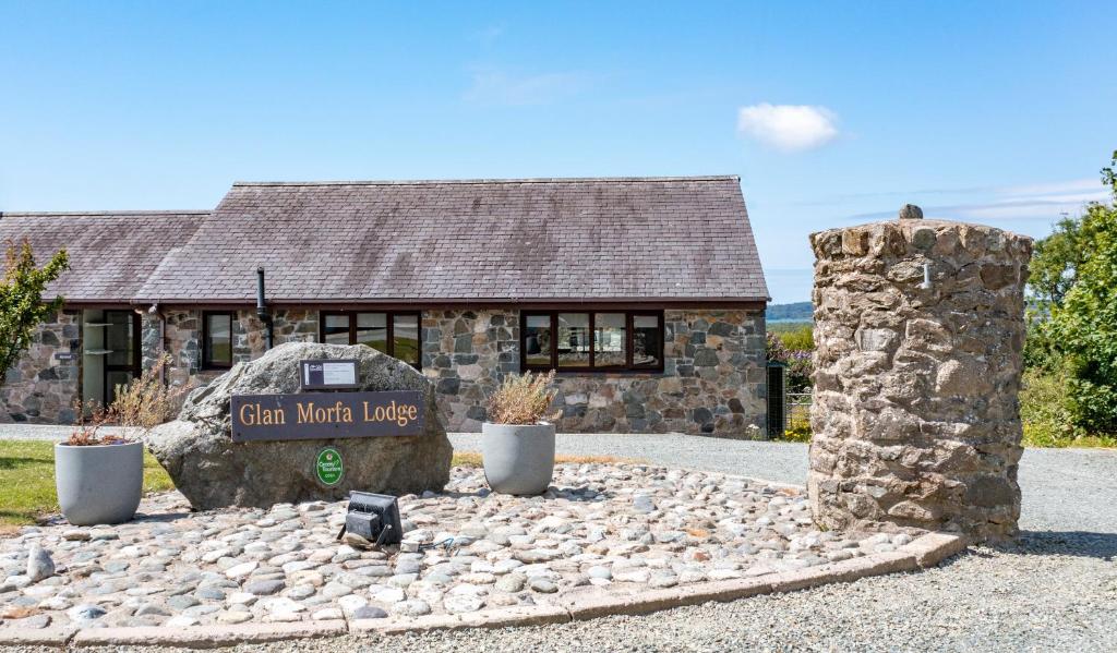 a stone building with a sign in front of it at Glan Morfa Lodge Retreat in Newborough