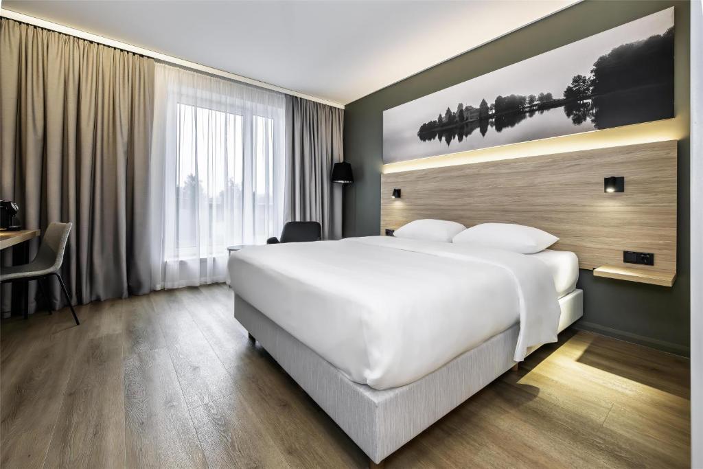 a hotel room with a large white bed and a desk at Park Inn by Radisson Vilnius Airport Hotel & Conference Centre in Vilnius