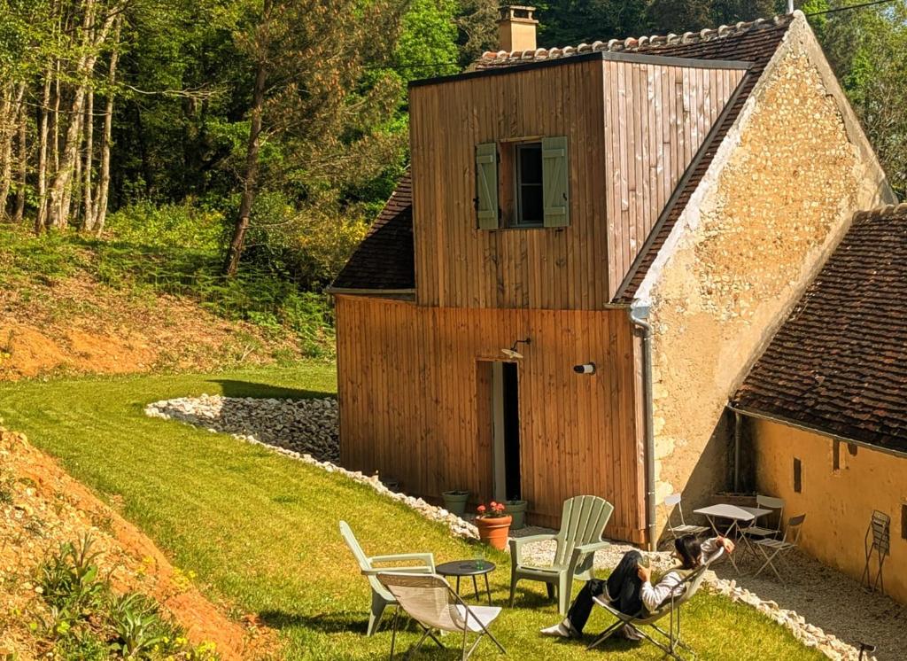 a woman sitting in chairs in front of a building at Hameau des Galottières-Perche, immersion nature in Ceton
