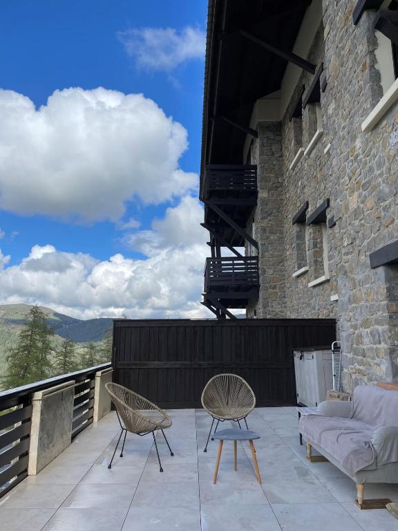 a patio with two chairs and a couch on a balcony at Studio cosy et sa terrasse in Beuil
