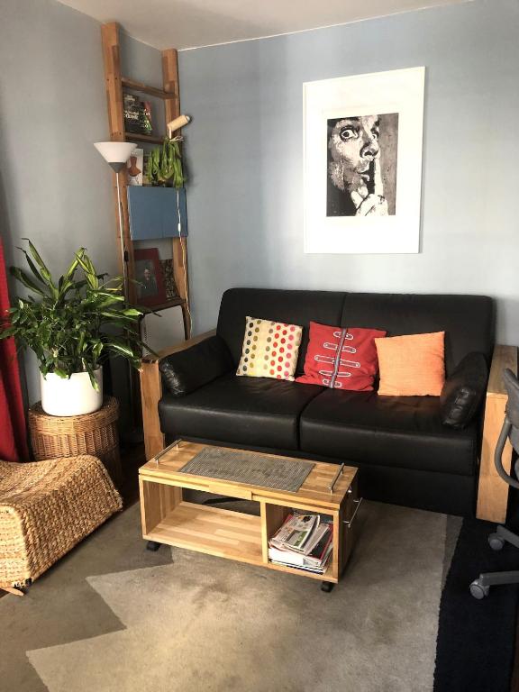 - un salon avec un canapé noir et une table basse dans l'établissement Deux Pièces des Arts-et-Métiers, à Paris