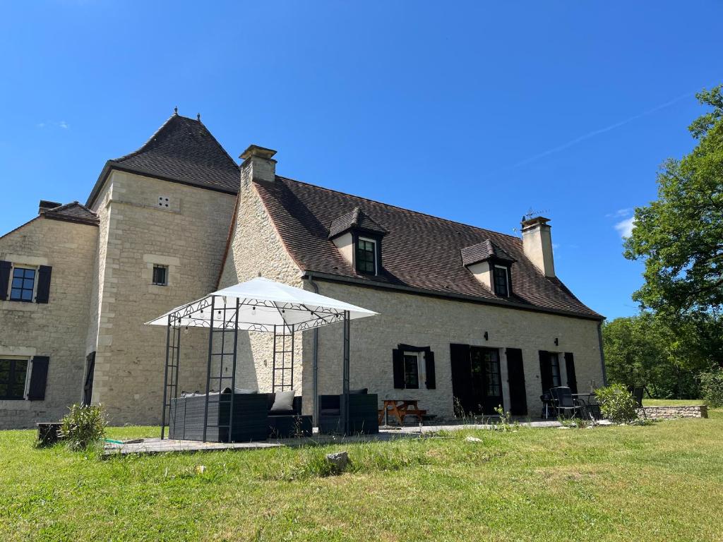 a large building with an umbrella in front of it at DomaineRossignol Acacia in Gourdon-en-quercy
