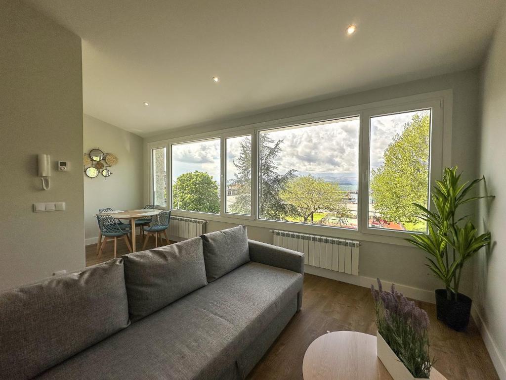 ein Wohnzimmer mit einer Couch und einem Tisch und Fenstern in der Unterkunft Apartamentos Marina Mar Vilagarcía 3000 in Villajuán