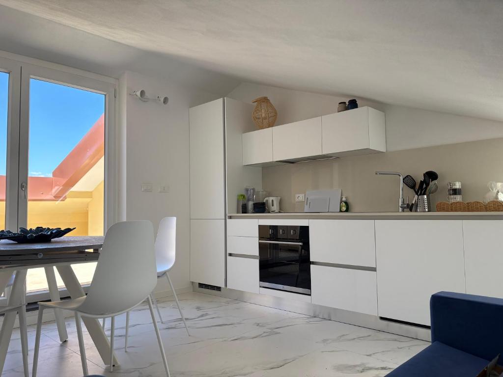 a kitchen with white cabinets and a table and chairs at Golfo Ameno Apartment in Portovenere