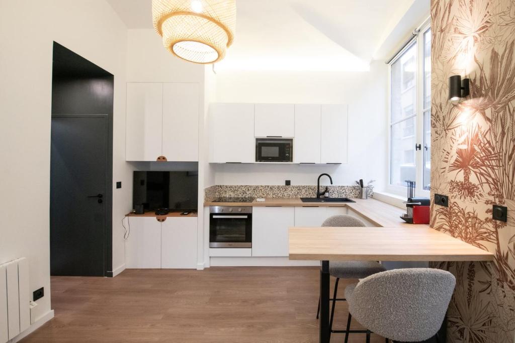 une cuisine avec des armoires blanches et une table en bois dans l'établissement Le Terrazzo - Elégant & Cosy- Pentes de la Croix Rousse, à Lyon