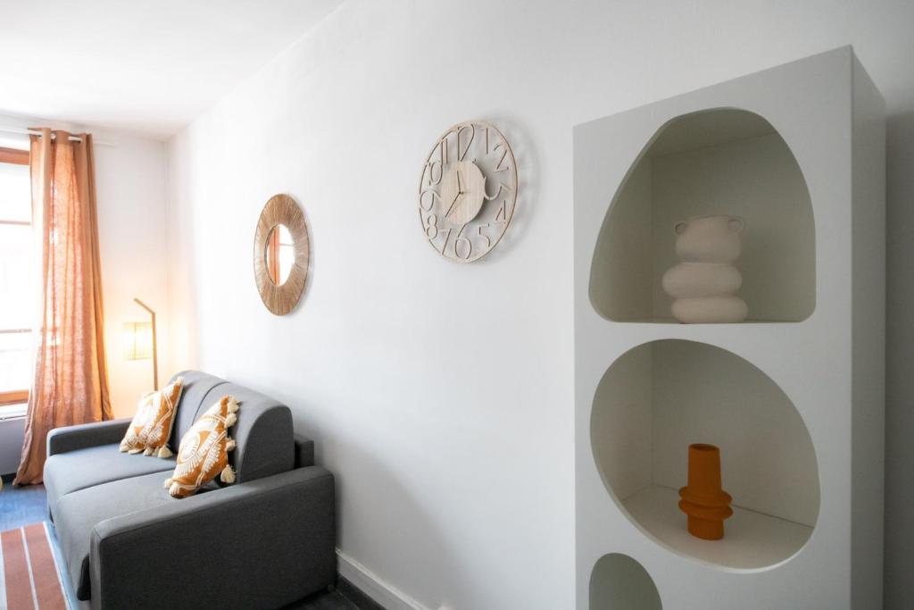 un salon avec un canapé bleu et des horloges murales dans l'établissement Le Moanda - Charpennes 15 mn du centre de Lyon, à Villeurbanne