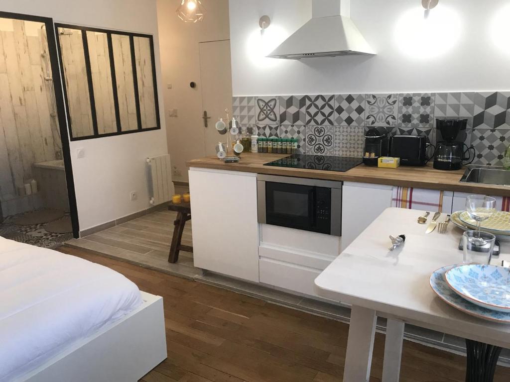 une cuisine avec des placards blancs et une table avec des assiettes. dans l'établissement La Suite de Léon appartement D - Lyon Garibaldi, à Lyon