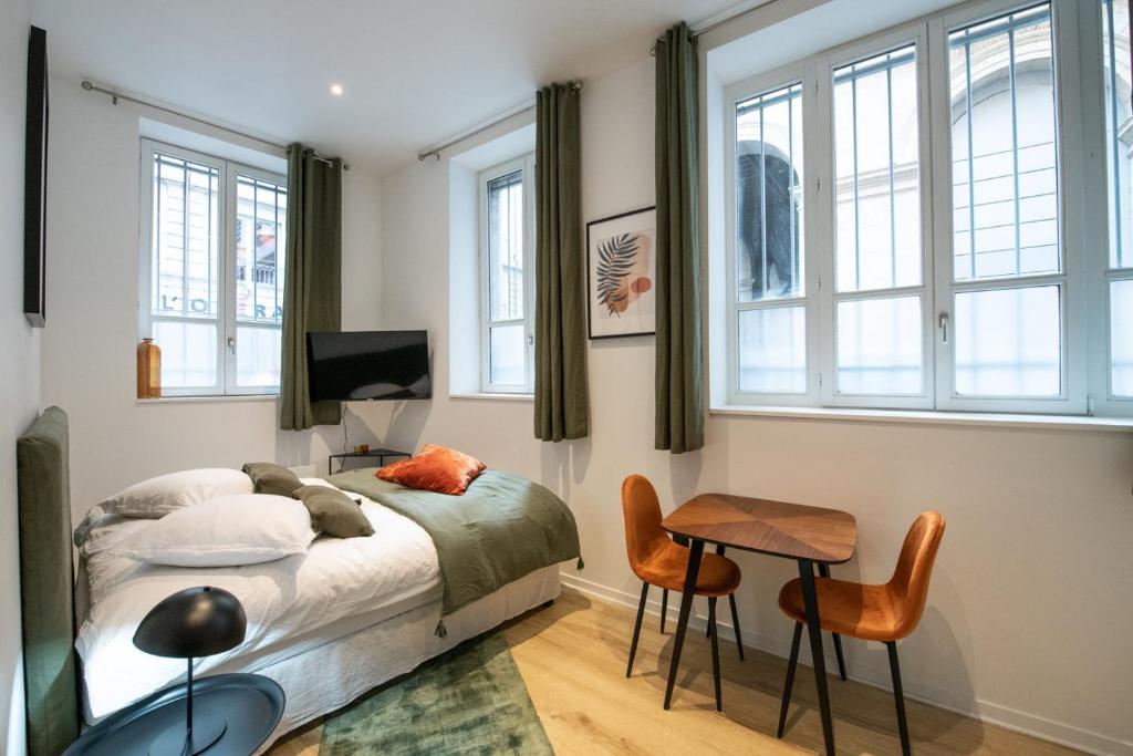 une chambre avec un lit, une table et des chaises dans l'établissement La Suite Opéra 1 - Hypercentre proche place des Terreaux, à Lyon
