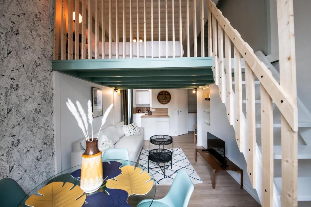Una sala de estar con una escalera y una mesa de cristal. en Le Gary - Appartement atypique refait à neuf - A deux pas Parc Tête d'Or, en Gare des Brotteaux