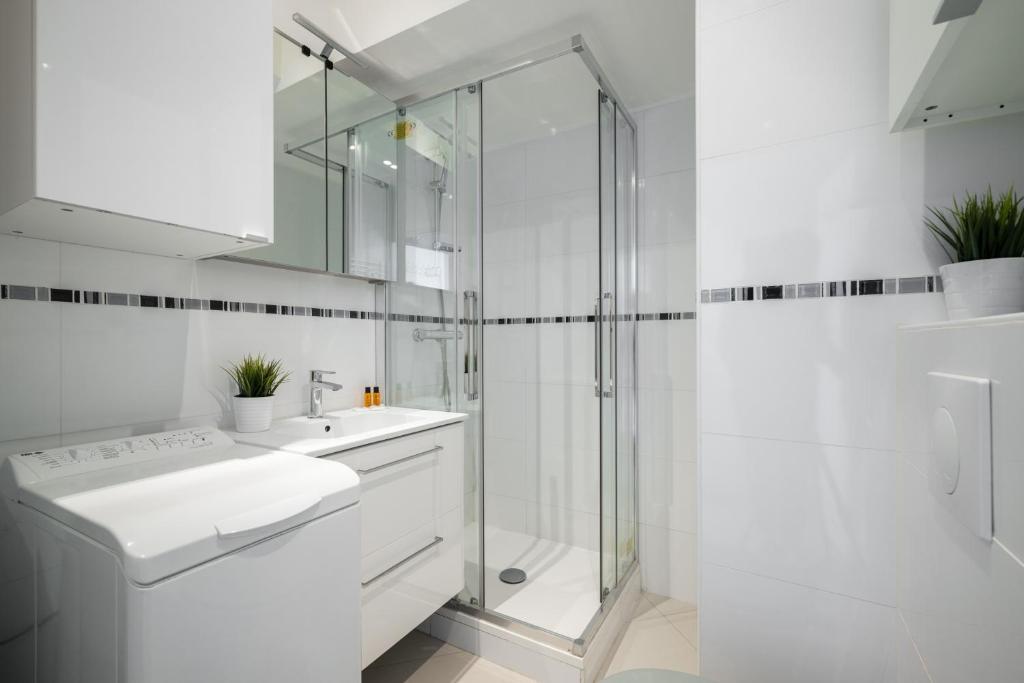une salle de bain blanche avec un lavabo et une douche dans l'établissement Rives d'or 2, Beautiful beachfront studio, beach access, AC, à Roquebrune-Cap-Martin