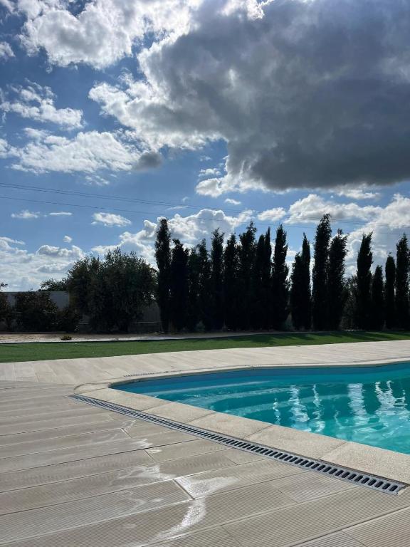 an empty swimming pool with a cloudy sky and trees at Monte do Carapetal in Amareleja