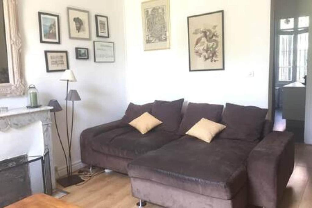 - un salon avec un canapé brun et une cheminée dans l'établissement Appartement en rez de jardin centre ville, à La Celle-sous-Gouzon