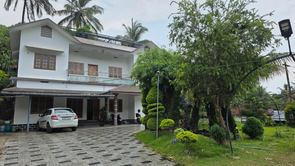 a white house with a car parked in the driveway at Serahs Homestay in Agali