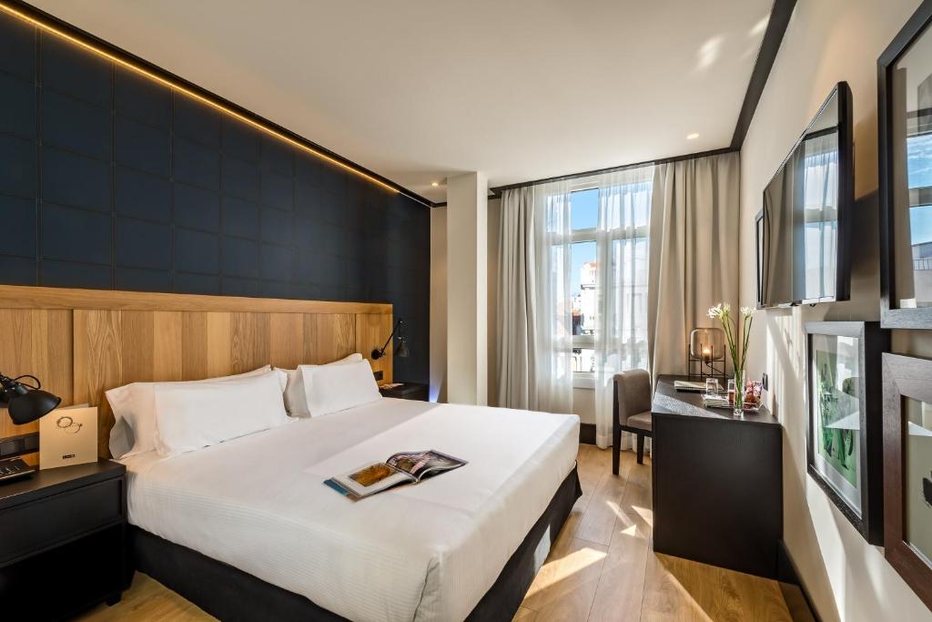 a hotel room with a bed and a desk at H10 Puerta de Alcalá 4 Sup in Madrid