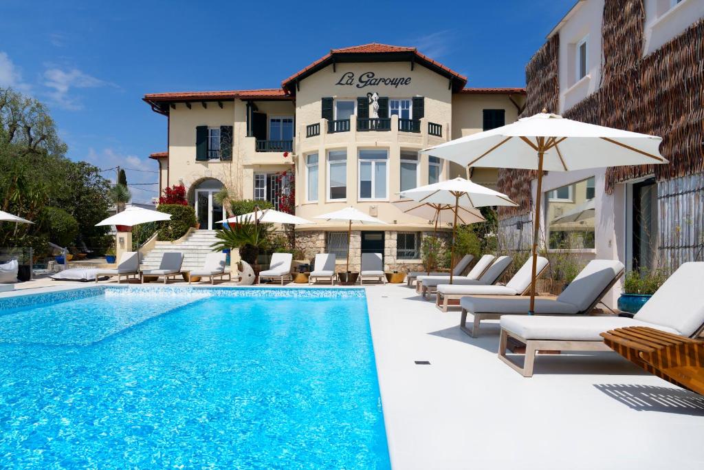 a pool with chairs and umbrellas next to a building at La Garoupe-Gardiole in Antibes