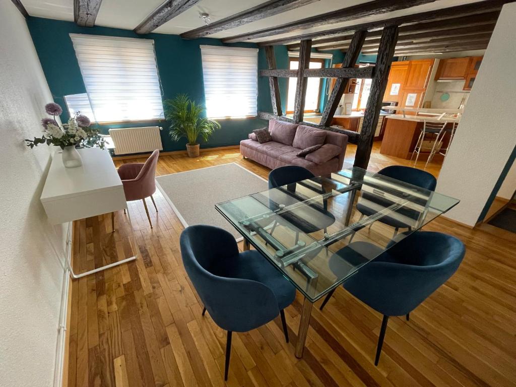 a living room with a glass table and blue chairs at Appartement spacieux - cœur historique de la ville in Barr