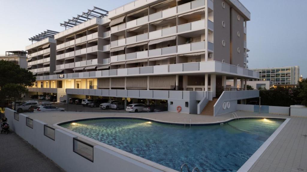 a building with a swimming pool in front of a building at Residence Itaca in Bibione