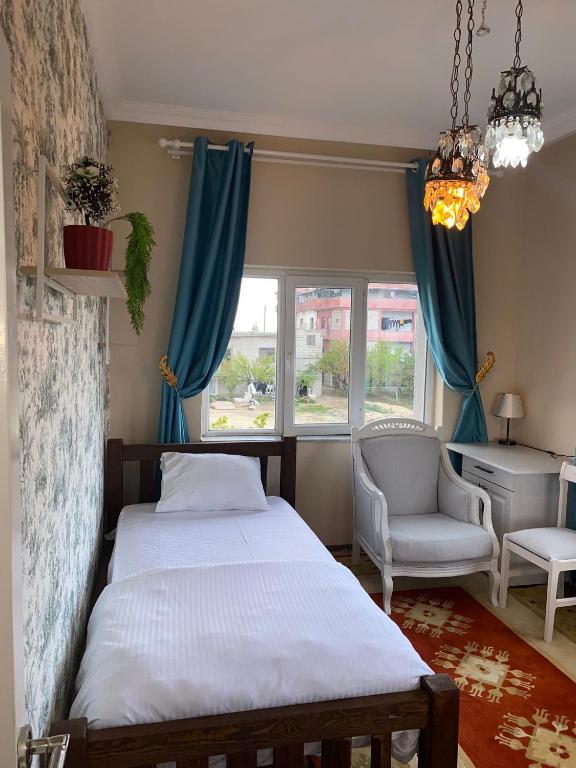 a bedroom with a bed and a chair and a window at Hibe Dede Konak in Ürgüp