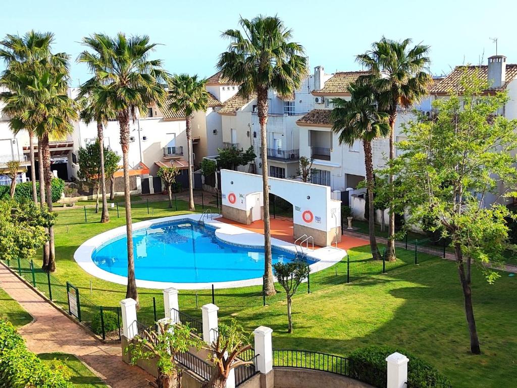 an apartment with a swimming pool and palm trees at Casa Playa Las Redes in El Puerto de Santa María