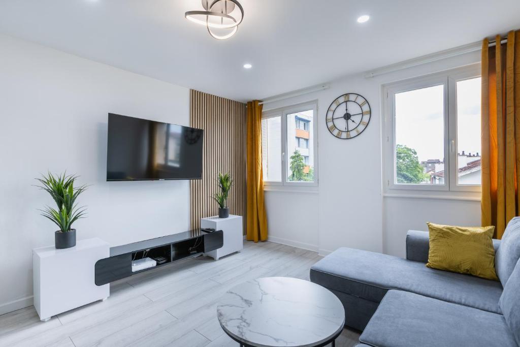 un salon avec un canapé et une télévision sur un mur dans l'établissement Meublé 3 chambres près Saint Jacques, à Clermont-Ferrand