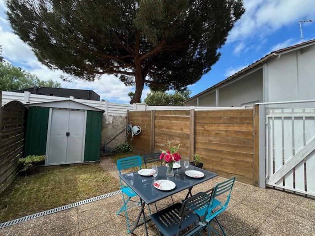 un patio avec une table et des chaises et une clôture dans l'établissement Maison calme avec jardinet, proche plage et Parc de Royan - FR-1-494-56, à Royan