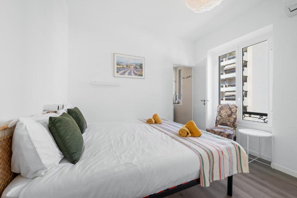 une chambre blanche avec un lit et une chaise dans l'établissement Le Botta, spacieux appartement famillial, centre ville de Menton, jardins Biovès, à 5 minutes de la mer, à Menton