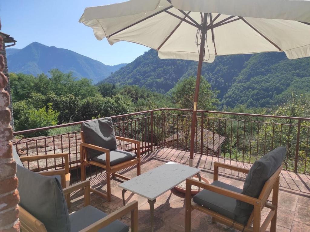Un patio con sillas y una sombrilla y una mesa. en Traditional Tuscan Farmhouse Lucca District - sleeps 6, en Diecimo