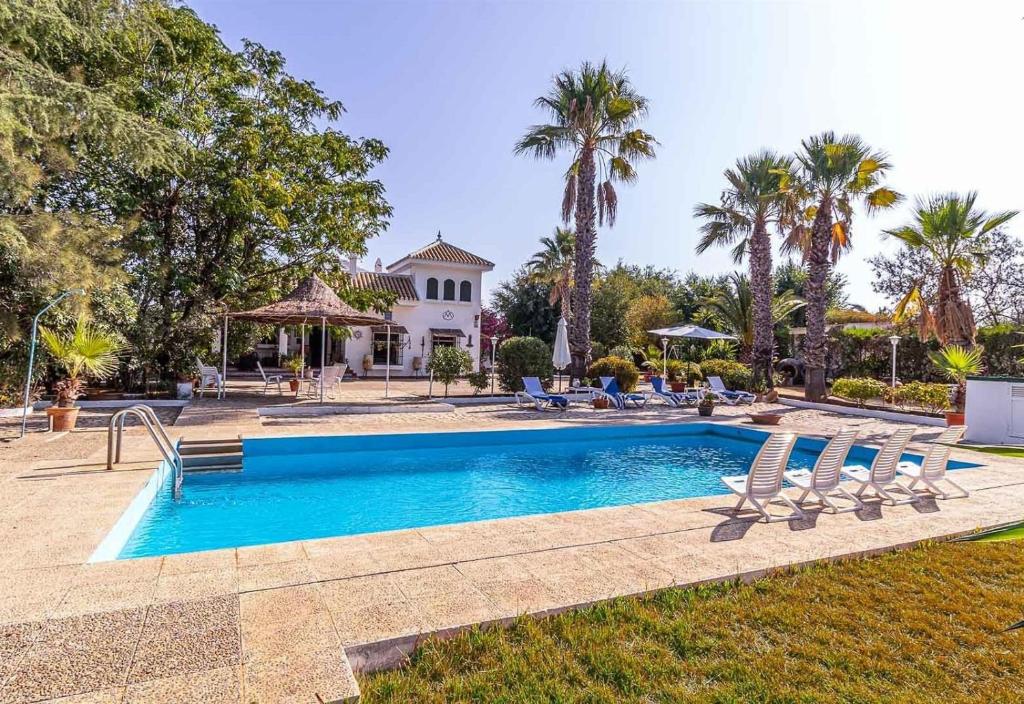 una piscina con sillas y una casa en Casa Rural Santa Ana, en Marchena