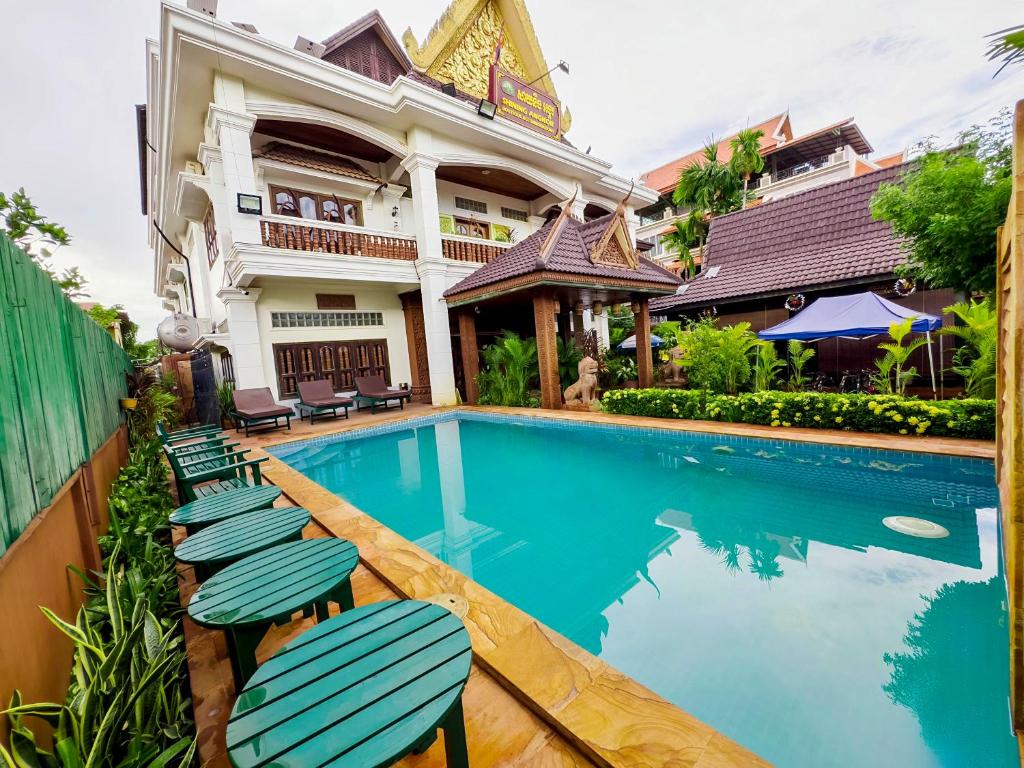 a swimming pool in front of a house with chairs at Shining Angkor Boutique Hotel in Siem Reap