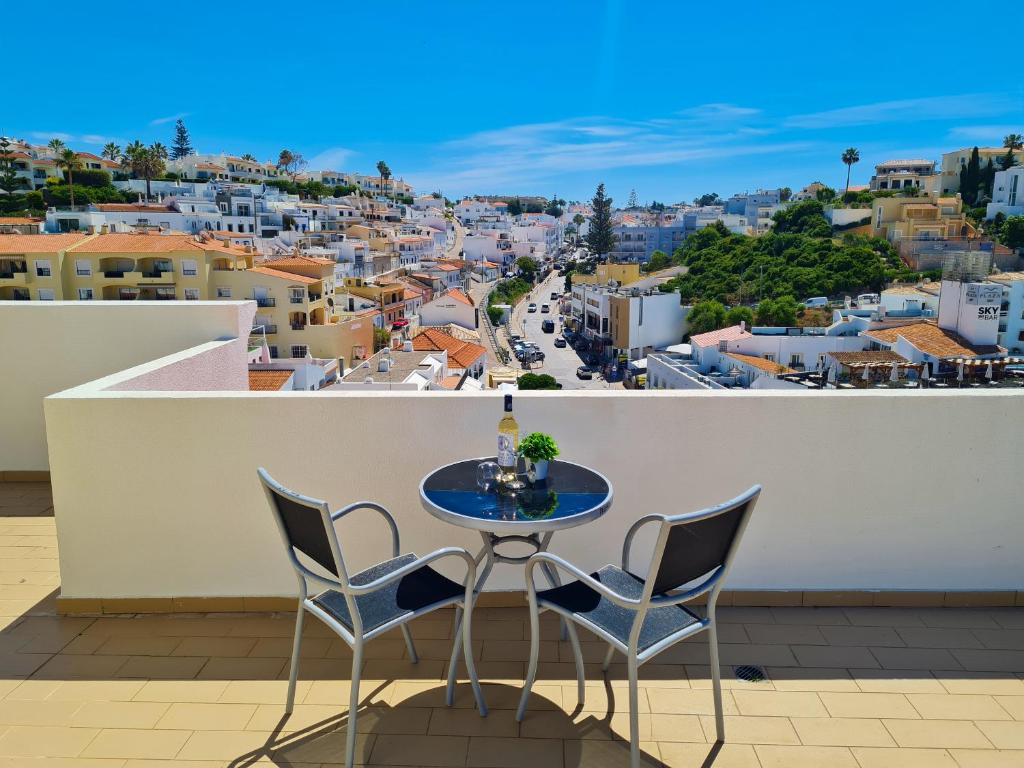 een tafel en stoelen op een balkon met uitzicht op een stad bij SÍTIO DO RAPOSO - Carvoeiro - WiFi, AC, Beach & Center 200m in Carvoeiro