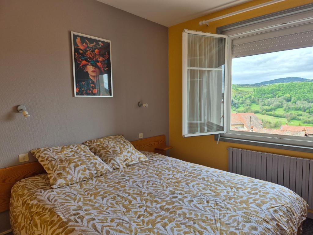 a bedroom with a bed and a large window at Gîte Bîn Vendüd Châ Nous in Le Monastier sur Gazeille