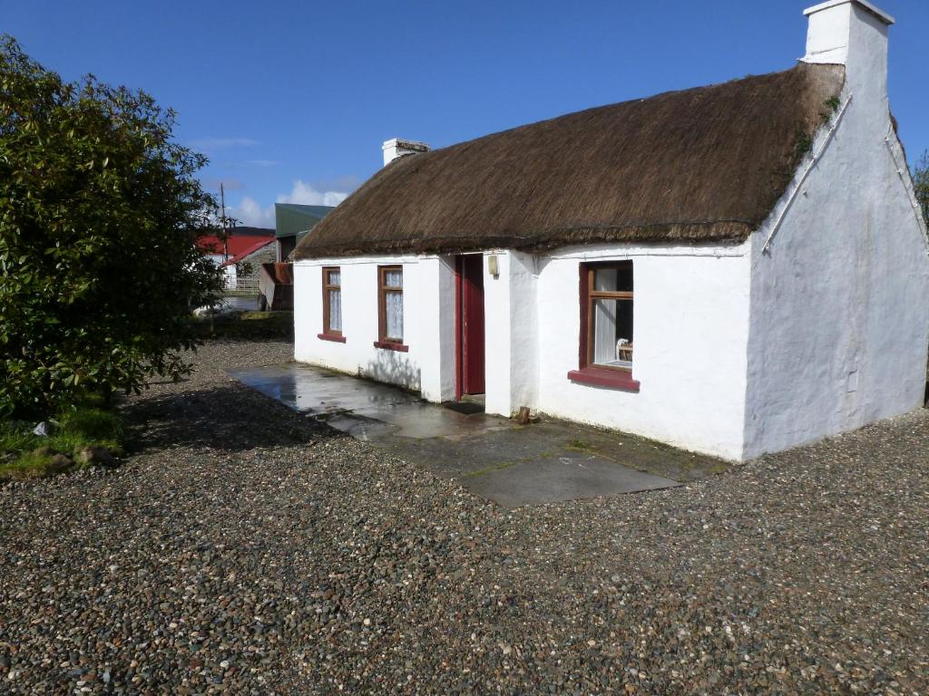 un pequeño edificio blanco con techo marrón en Tigín Tuí en Carndonagh