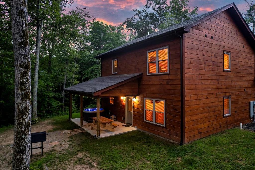 eine Blockhütte im Wald mit einer Veranda in der Unterkunft Serene Cabin with Hot-tub and Fire Pit in Pigeon Forge, Tennessee in East Fork