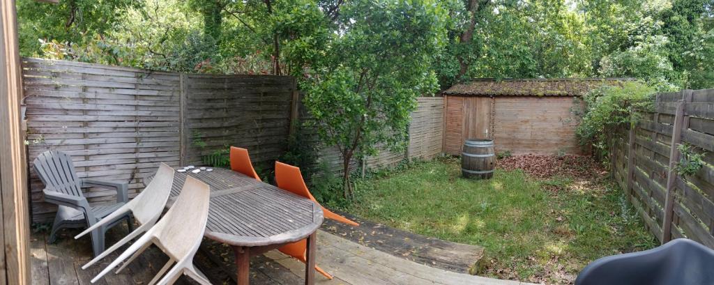 un patio avec une table et des chaises et une clôture dans l'établissement Cottage à 600 mètres du Lac de Sanguinet, à Sanguinet