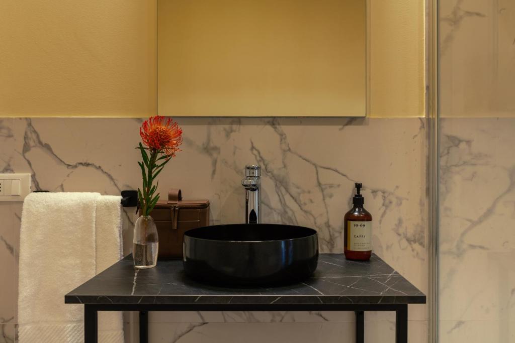 a bathroom with a sink and a vase with a flower on a table at Bob W Ticinese in Milan