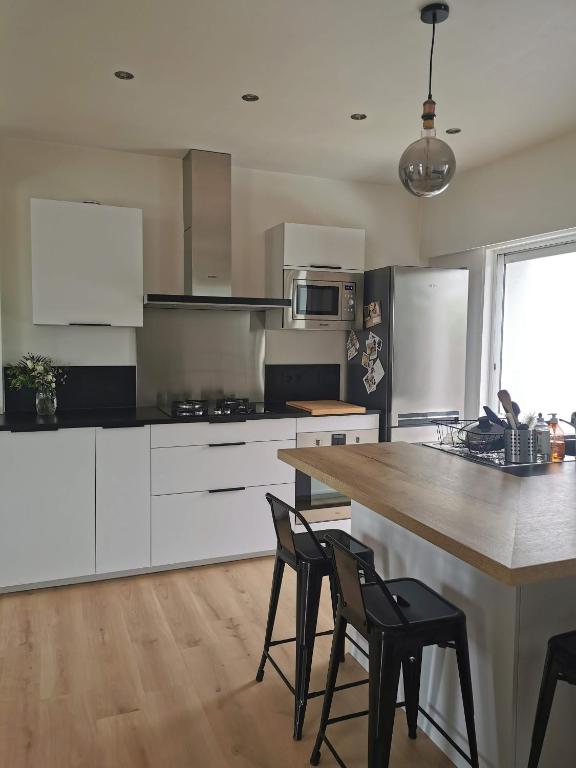 une cuisine avec des armoires blanches et une table et des chaises dans l'établissement Maison agréable plouharnel, à Plouharnel