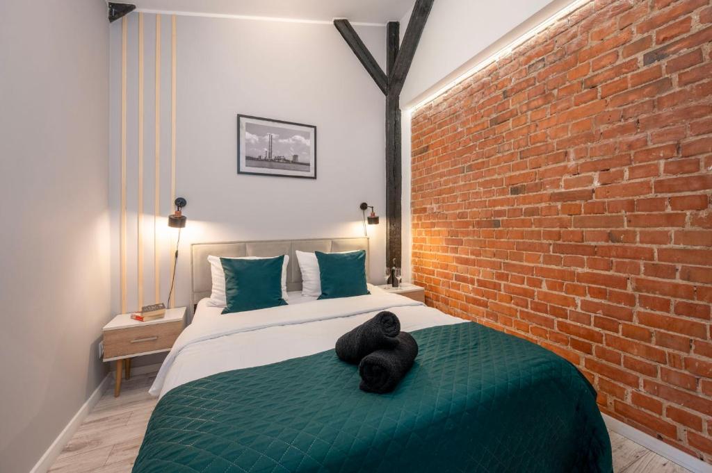 a bedroom with a bed with a brick wall at Kościelna Loft SPA Apartaments in Rybnik