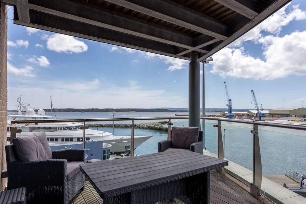 a porch with a wooden table and chairs and a boat at Panorama - 180-Degree Harbour Views in Poole