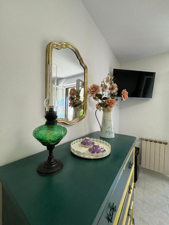 a green table with a mirror and a vase with flowers at Jungle Rooms in Cetara