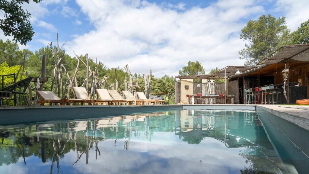 a swimming pool with lounge chairs and a house at Charming villa in the heart of the Mediterranean Garrigue in Nîmes