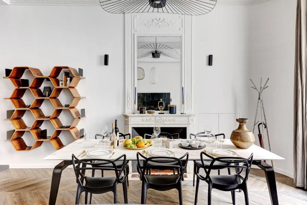 une cuisine blanche avec une table avec des chaises et une cheminée dans l'établissement appartement de Luxe haussmannien aux champs-elysees, à Paris