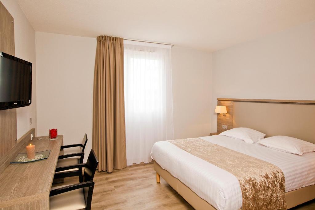 Habitación de hotel con cama, escritorio y TV. en Séjours & Affaires Grenoble Marie Curie, en Grenoble