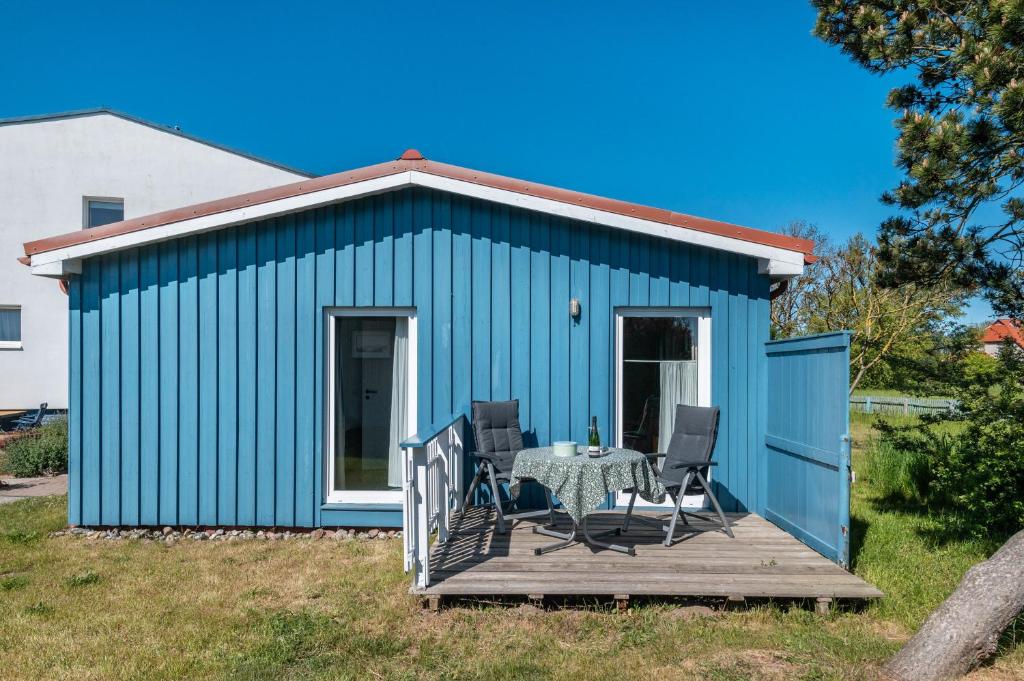un cobertizo azul con una mesa y sillas en una terraza en Möve Aba Bungalow 61, en Rerik