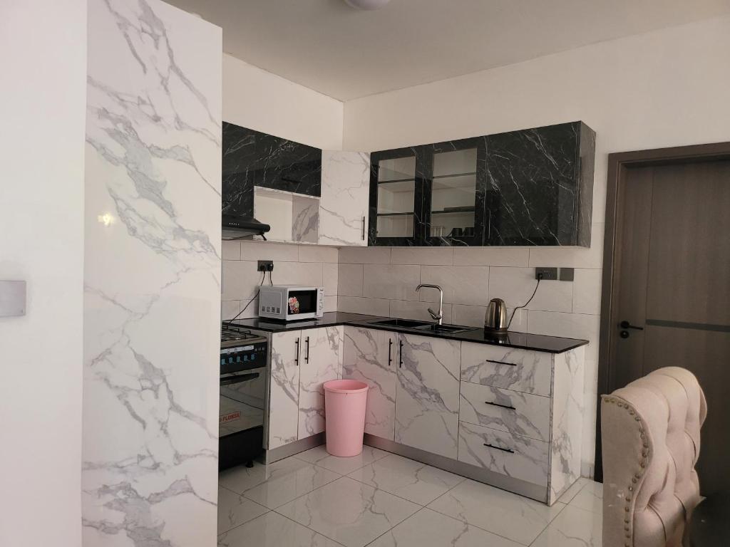 Wintana Apartments Kigali في كيغالي: مطبخ مع أسطح رخامية وسلة قمامة وردية اللون